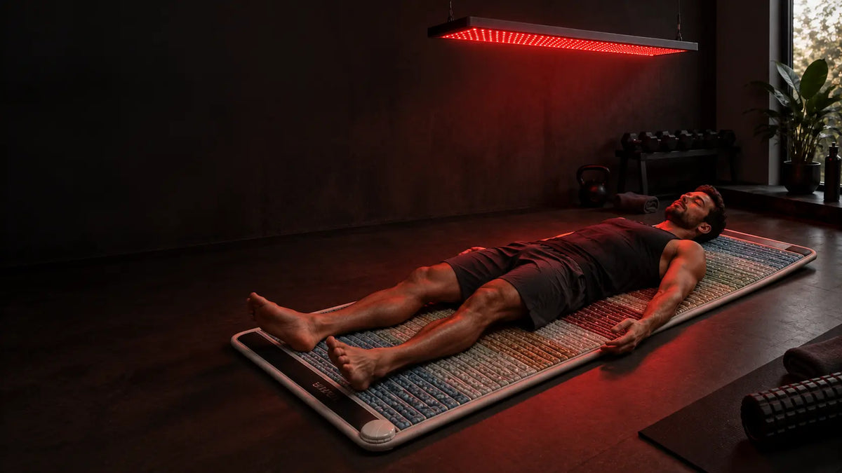 Athlete recovering on a LiveWell Restore PEMF mat beneath a red light panel